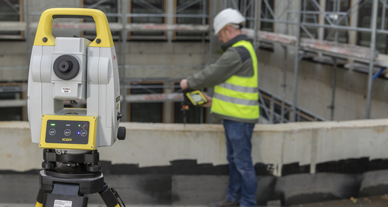 Construction worker in yellow vest setting out with a short construction prism pole on concrete slab with the Leica iCT30 layout tool.